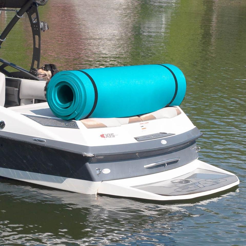 A Frawgs teal floating mat rolled and strapped on the swim deck of a wakeboard boat